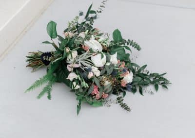 Beautiful bridal bouquet with ivory roses, ivory peonies, thistle, rice flower, air plants, lisianthus, eucalyptus, greenery, and ferns.